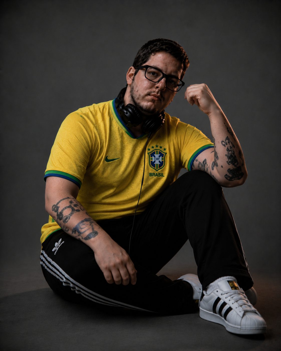 DJ Lipe sentado no chão com a camisa amarela